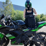 Femme motard en train de chercher ses affaires dans un sac militaire 30l posé sur une ninja Kawasaki.