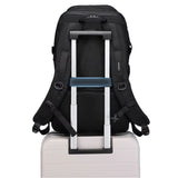 Sac militaire noir attaché à une valise grâce à sa sangle arrière pour un transport pratique