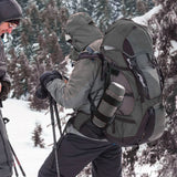 Randonneur équipé d’un sac et porte-gourde noir en montagne enneigée
