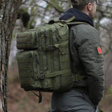 Sac a dos 50l militaire - Homme en tenue Bush Craft vert olive portant le sac.