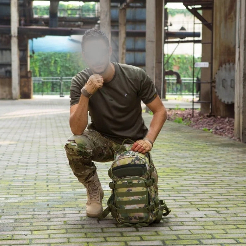 Homme en tenue militaire avec à ses pieds un sac à dos tactique 25l camouflage digital.