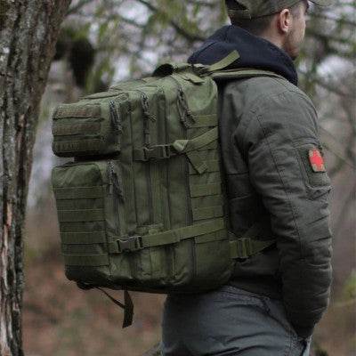 Homme en tenue de bush Craft avec un sac à dos tactique vert de 50L.