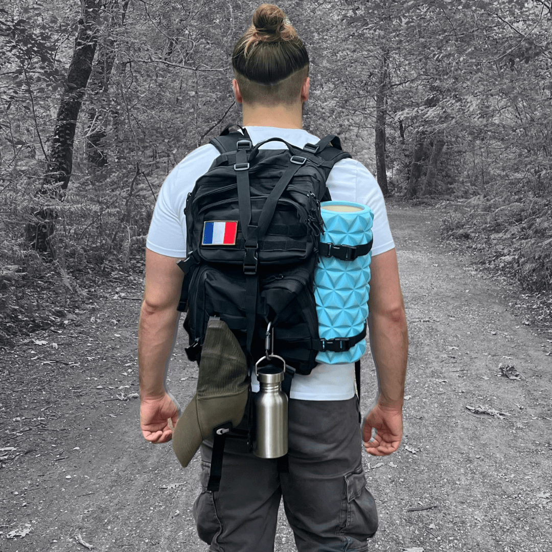 Athlète qui pose avec un sac à dos militaire noir avec des objets attachés au système molle intégré.